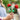 lego flowers 40460 roses 120 piece set. shows a close up of a woman holding the 2 lego roses by the stems.